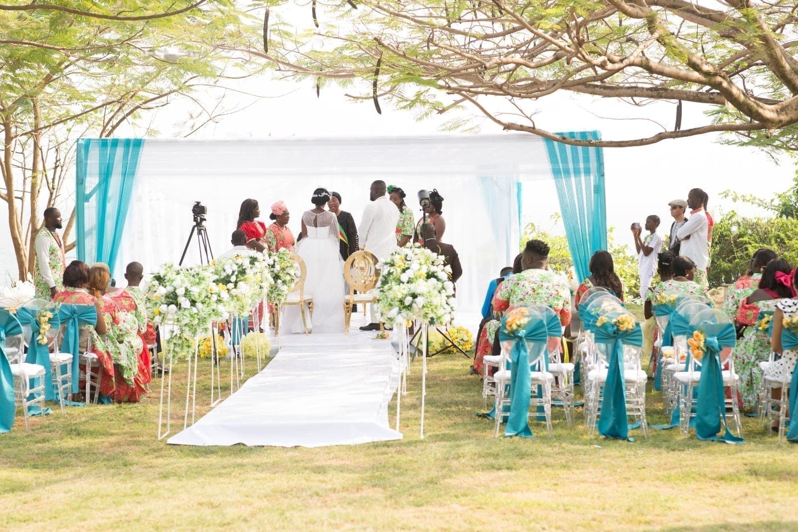 A couple exchange vows in front of their guests, under a flower-dressed arch