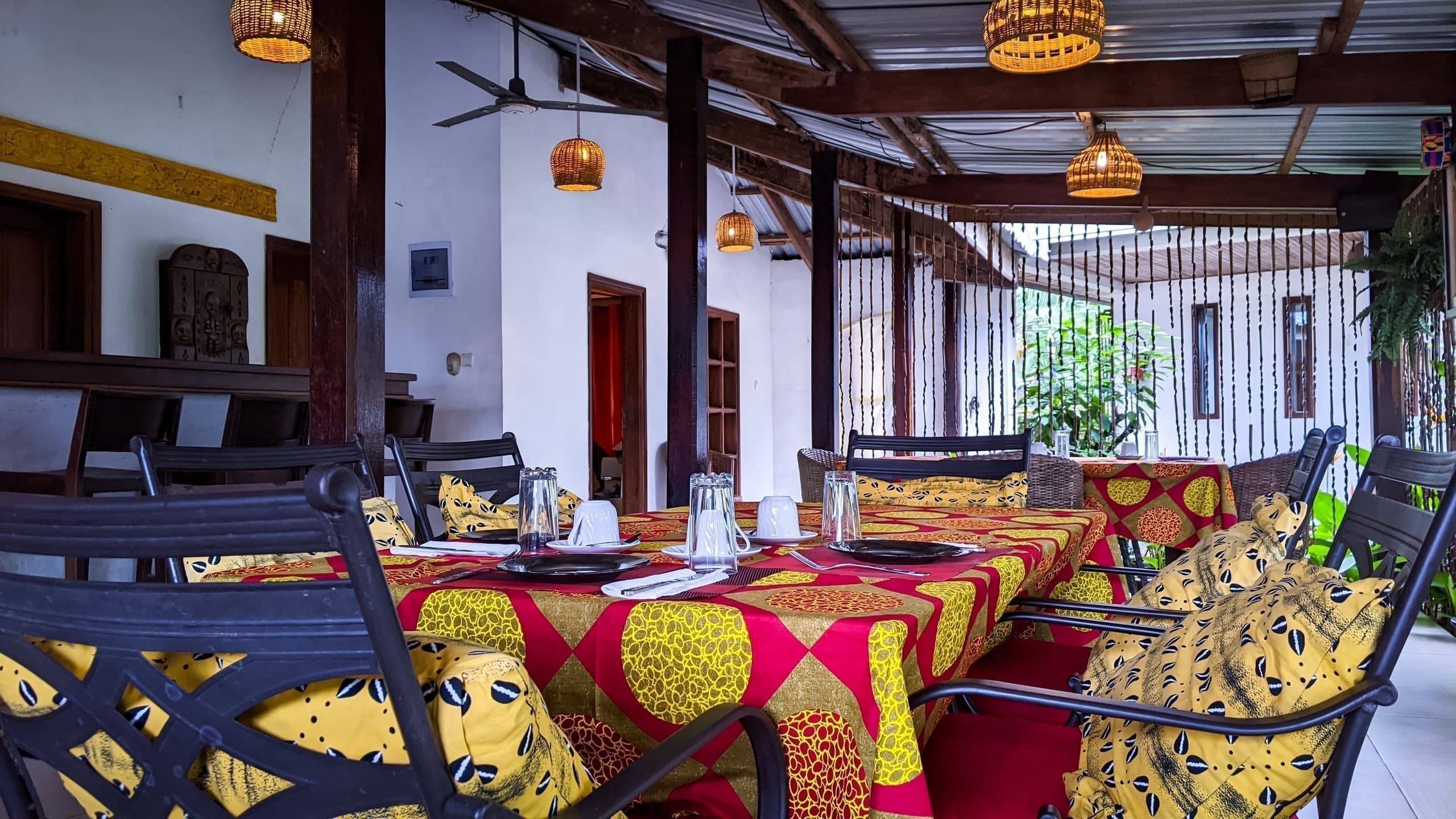 The restaurant veranda at dusk, tables set beneath rattan lanterns