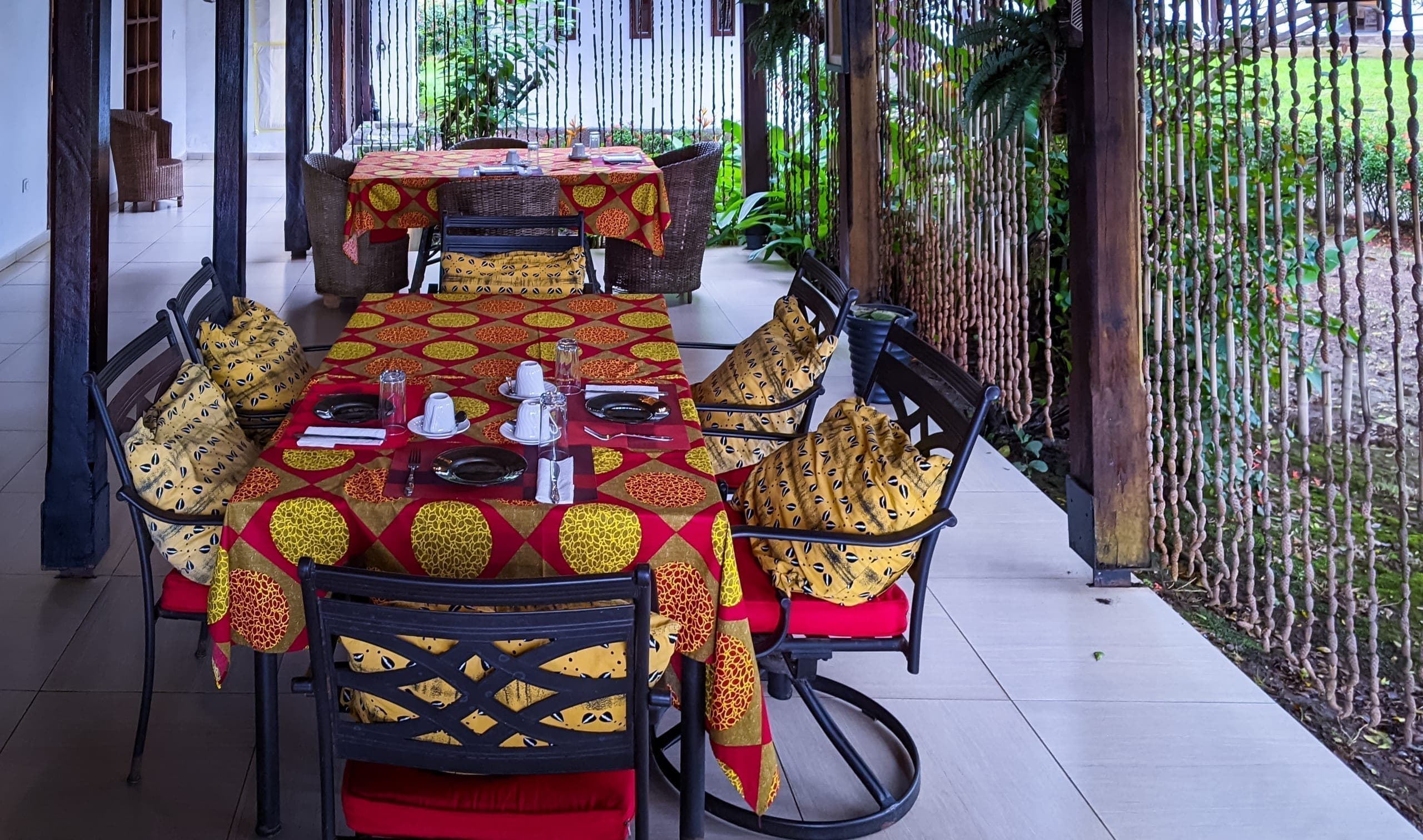 The veranda tables set for breakfast, garden visible through the bamboo curtain