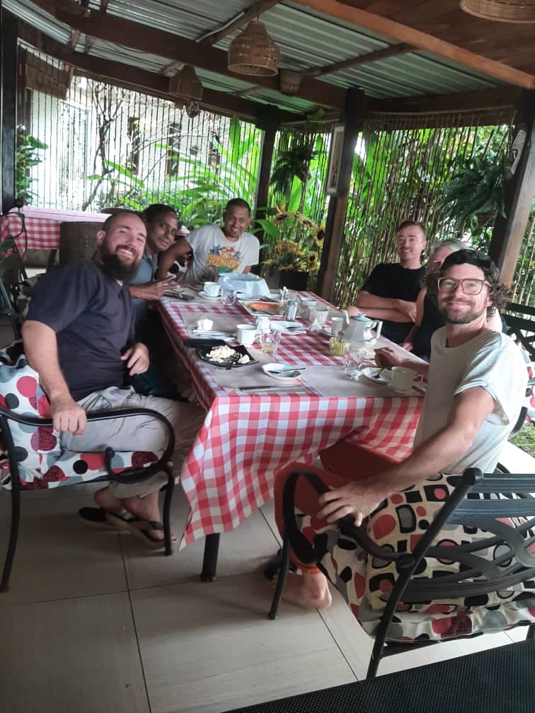 Guests sharing a meal together at a long table on the veranda