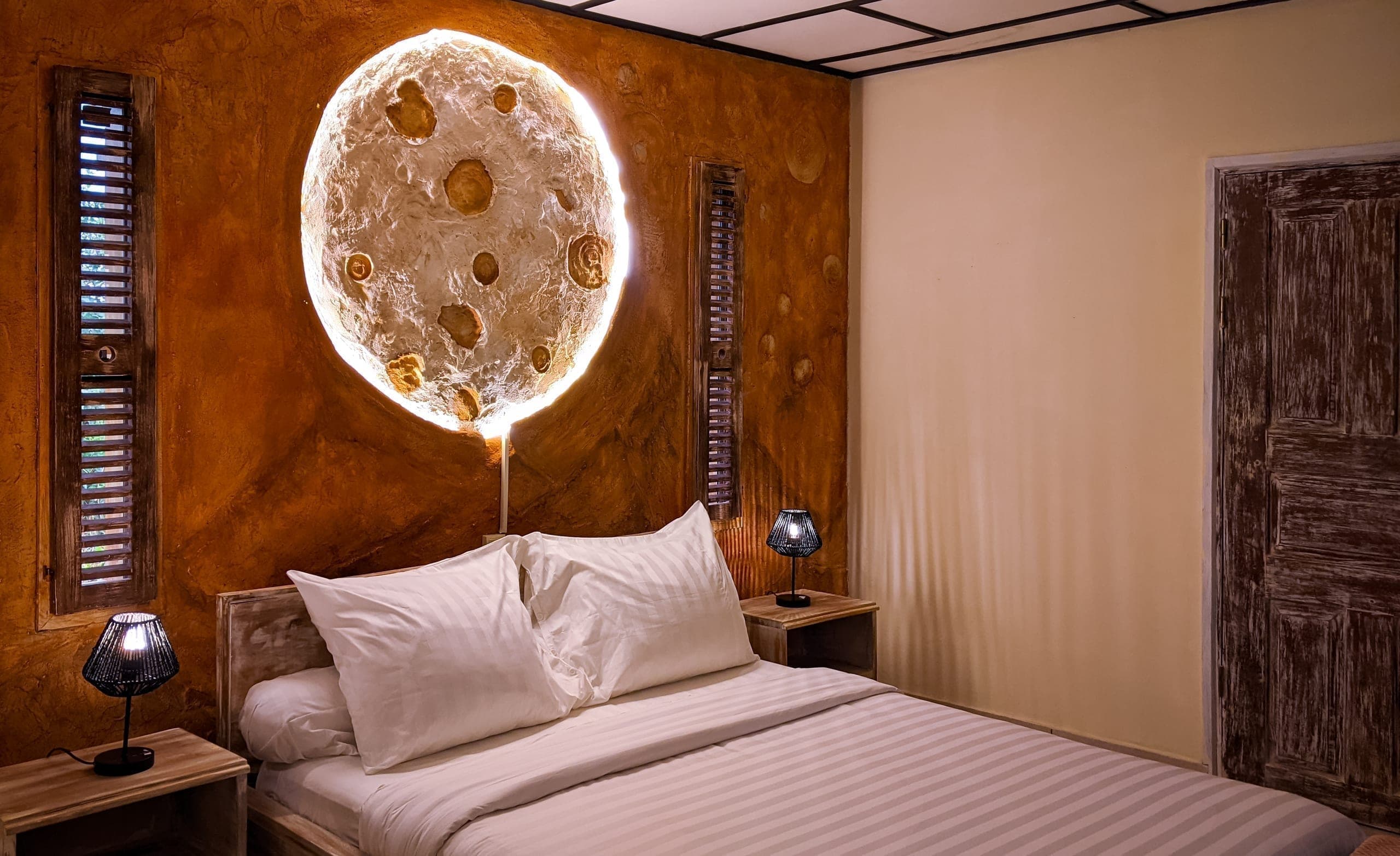 Bed beneath a round, backlit moon headboard