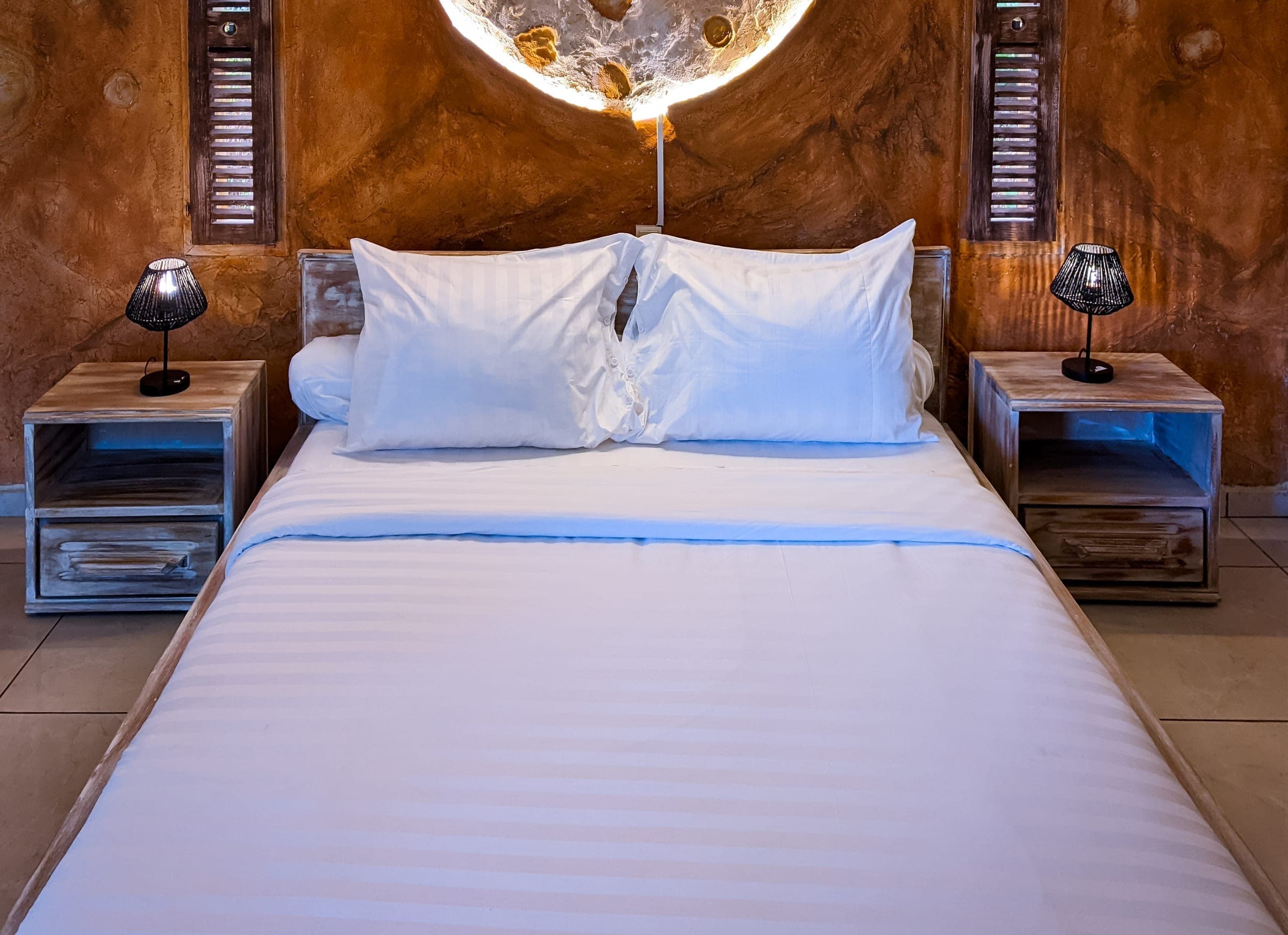 Bed centered beneath the moon headboard, lit lamps on both nightstands