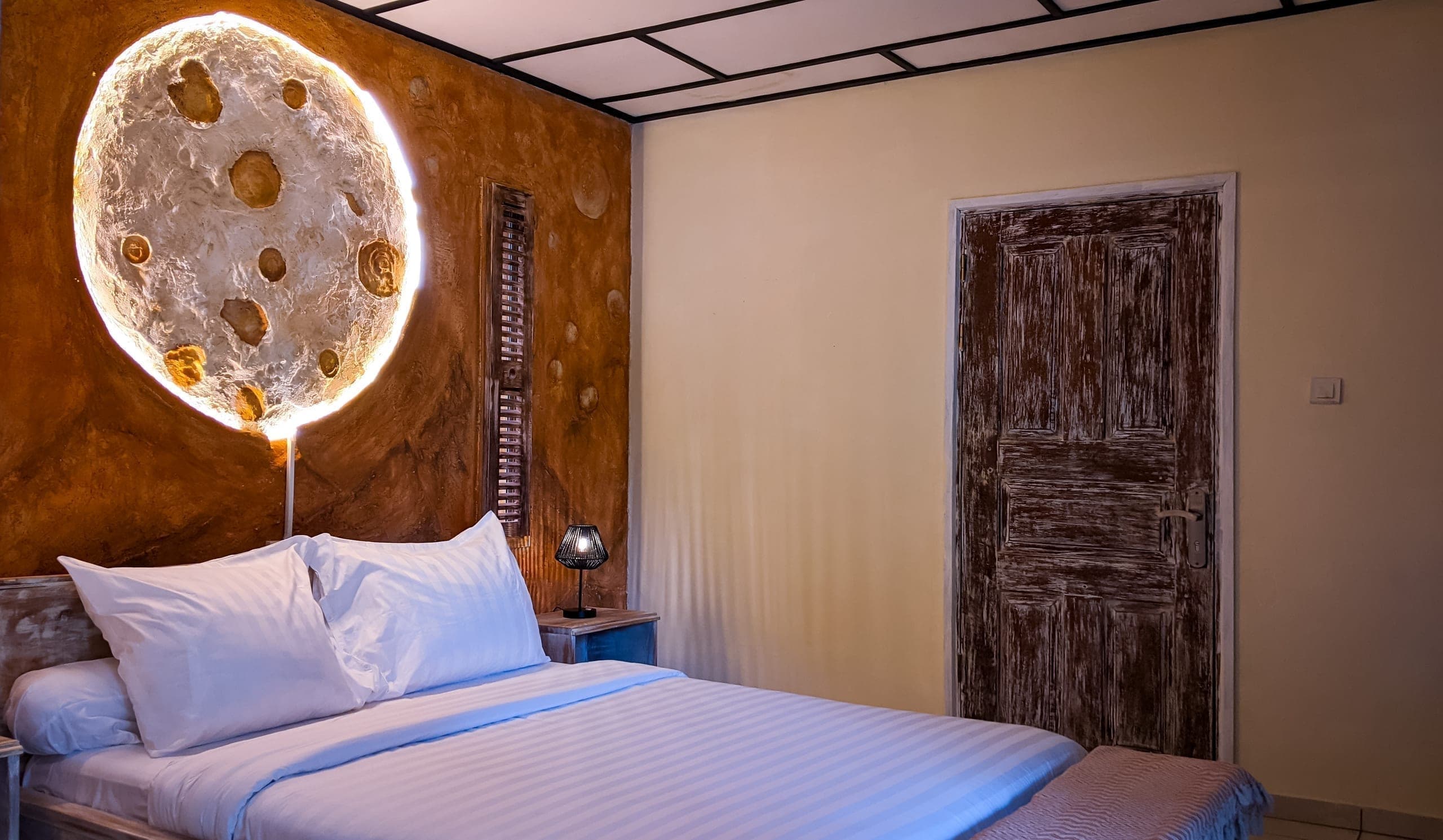 The bed and its moon headboard, seen from the foot of the bed