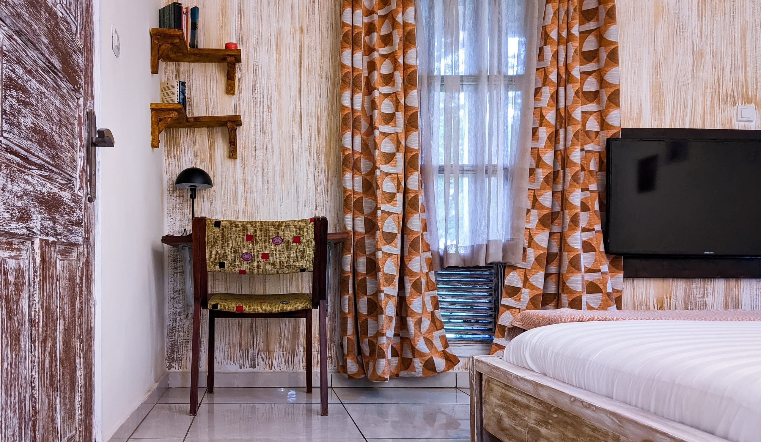 Writing desk and patterned chair beside the curtained window