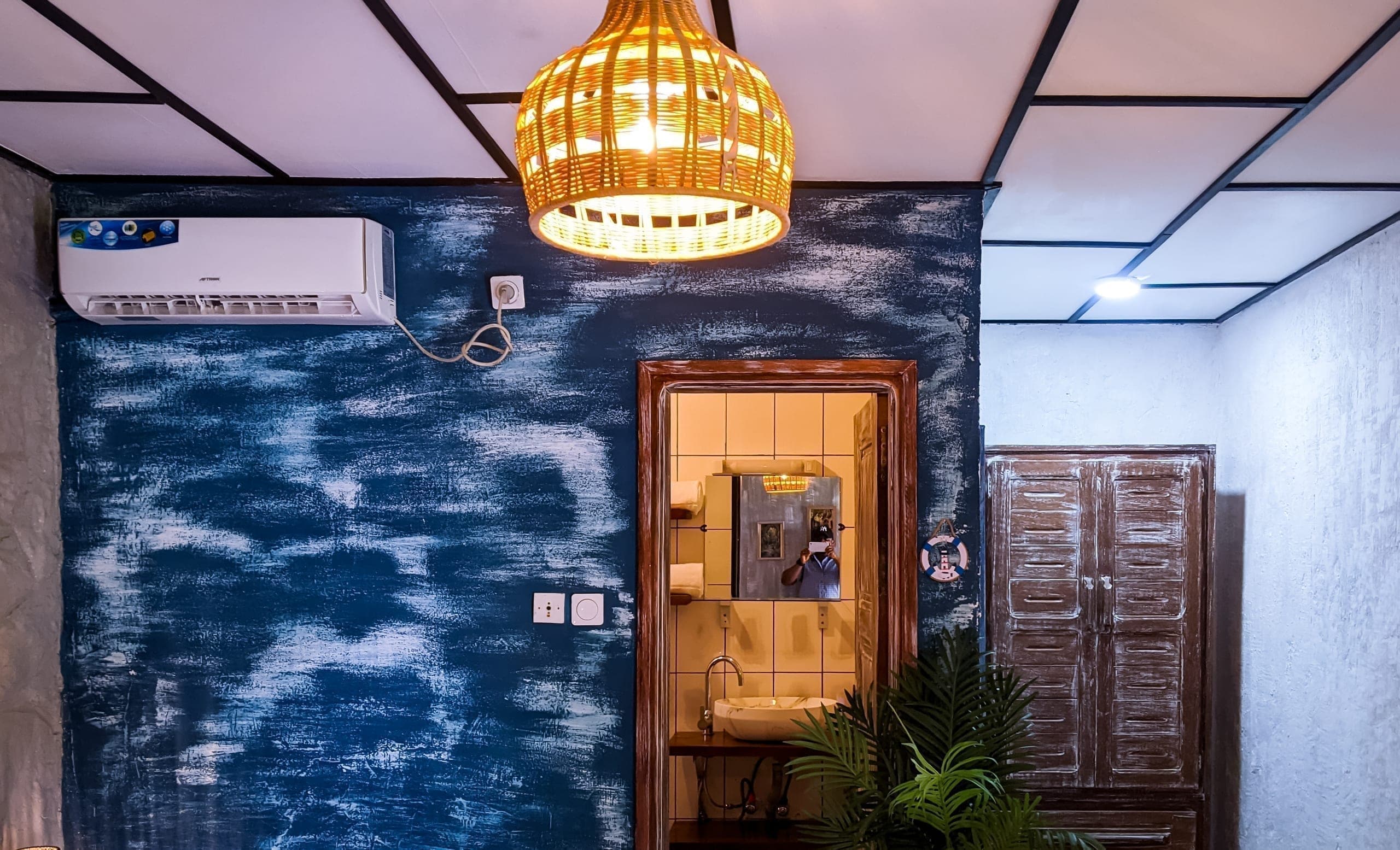 Indigo accent wall with woven pendant light, doorway to the bathroom