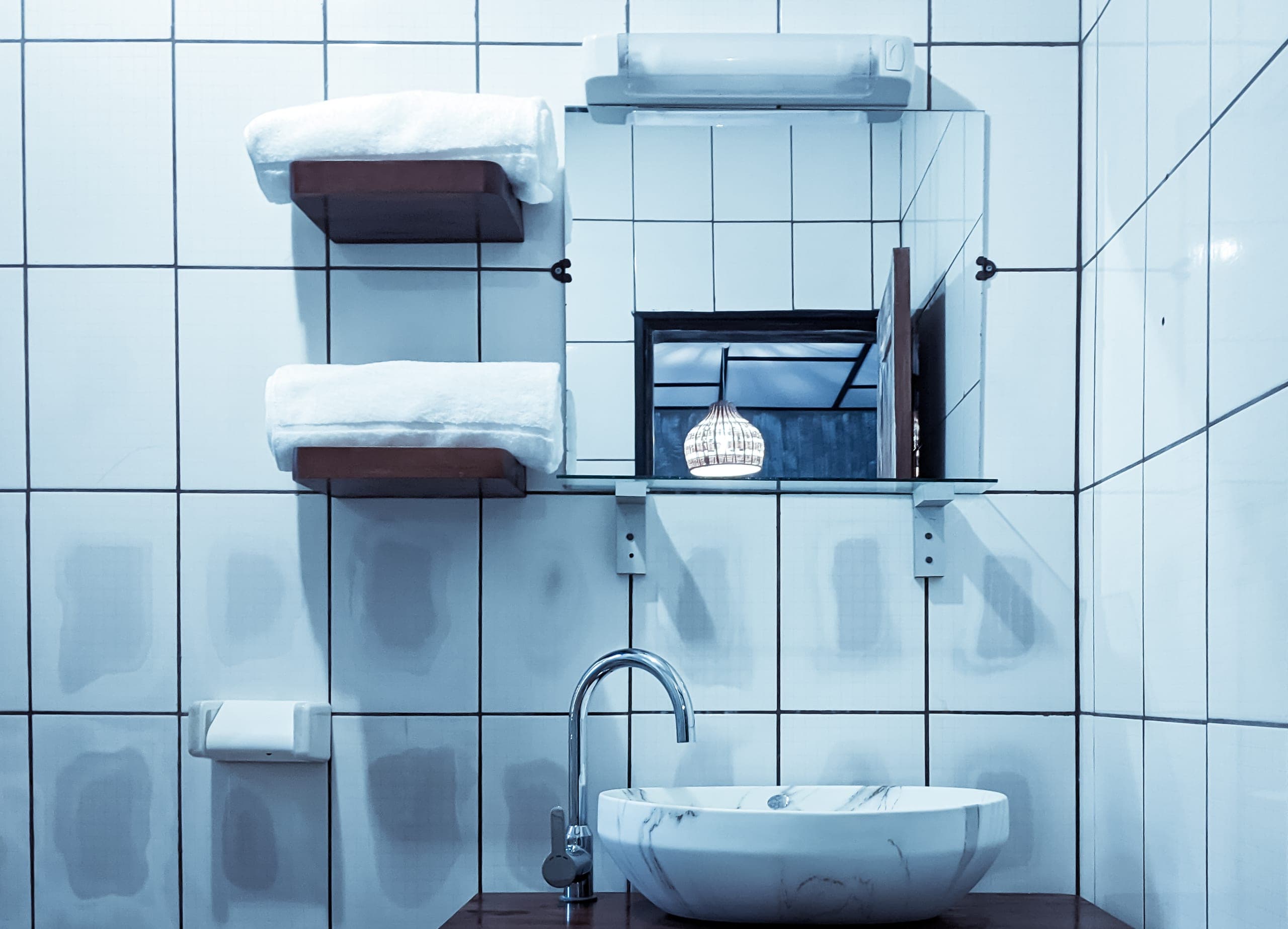 Folded towels and the marble sink, mirror reflecting the room beyond