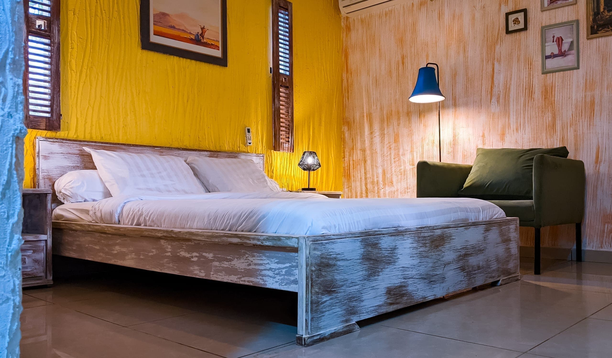 Bed and green armchair sitting corner, warm ochre walls