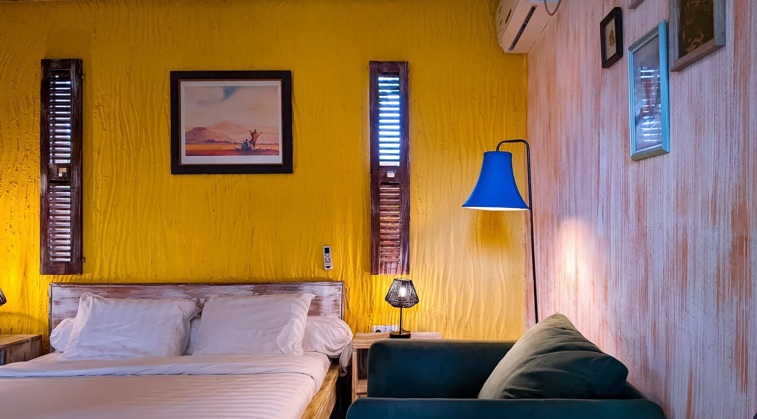 Wide view of the room: bed, shuttered windows, and sitting corner